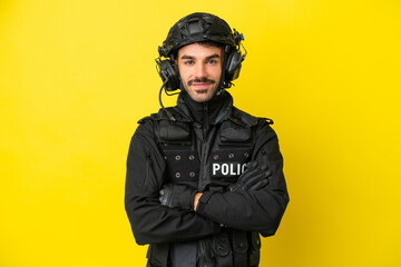 SWAT caucasian man isolated on yellow background keeping the arms crossed in frontal position