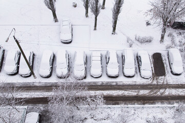 First snow. Cars under snow on a parking after blizzard, snowfall