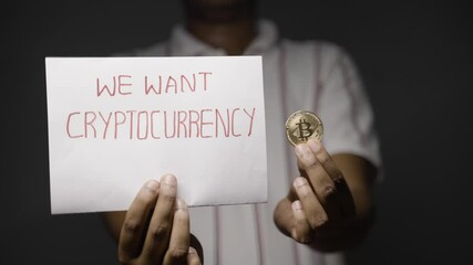 Maski, India - 26 November, 2021 : Concept of Cryptocurrency or bitcoin supporter showing by unrecognizable man with bitcoin and we want cryptocurrency sign board in hand.