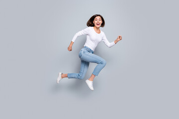 Photo of sweet cute young woman wear white outfit jumping high running fast smiling isolated grey color background