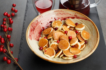 Dutch mini pancakes called poffertjes with red berries and tea. front view