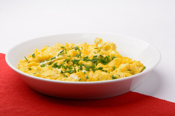 scrambled breakfast eggs on a white plate with red and white background