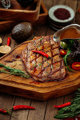Grilled beef steak with salad and sauce on wooden background