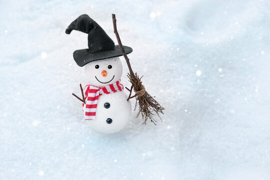 cute snowman in witch hat and broomstick on snow, natural winter background. New Year and Christmas holiday. festive winter season concept. copy space