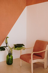 Mid-century retro chair and tropical home plant in bottle against white and ginger wall. Modern aesthetic minimalist home, living room interior design concept © Floral Deco