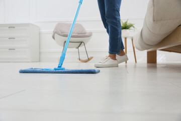 Woman cleaning parquet floor with mop at home, closeup