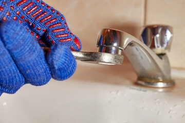 The plumber replaces the old, rusty water tap filter with a new one. The profession of plumber.