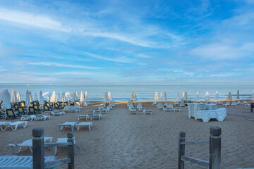 Fototapeta na wymiar Beach views, Sun loungers, umbrellas, flags and small wavy coastline in Antalya Side. Selective Focus.