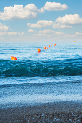 slightly wavy sea surface and orange marking pontoons. a small fishing boat in the distance. Selective Focus. No People.