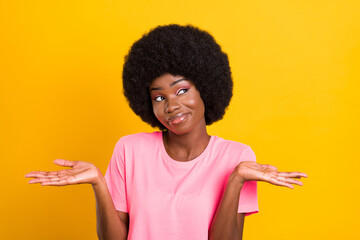 Photo of young black girl shrug shoulders clueless confused think look empty space isolated over yellow color background