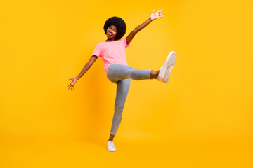 Full body photo of hooray millennial lady dance wear pink t-shirt jeans sneakers isolated on yellow color background