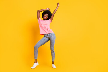Fototapeta na wymiar Full size photo of funny millennial lady dance wear pink t-shirt jeans sneakers isolated on yellow color background