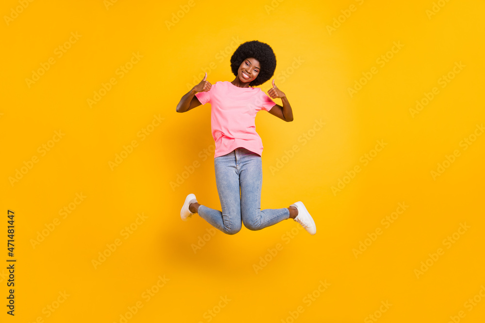 Sticker Full size photo of cool millennial lady jump show thumb up wear pink t-shirt jeans isolated on yellow color background