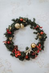 Christmas wreath, decoration in the house in the pre-Christmas period in the form of a wreath of fir branches with Christmas toys and decorations, fixed vertically on the wall.