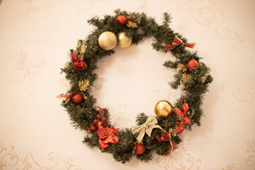 Christmas wreath, decoration in the house in the pre-Christmas period in the form of a wreath of fir branches with Christmas toys and decorations, fixed vertically on the wall.