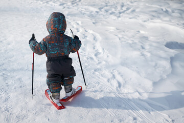 The kid takes his first steps on skis. Concept: introduction to sports from an early age. Copy space.