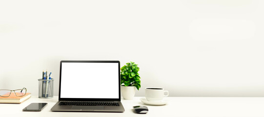 A working concept using technology, notebook, smartphones, devices. Blank white screen laptop on a white table in the office. Copy space on right for design or text, Closeup, Gray, and blur background