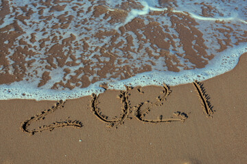 Years written on the sand by the Sea. The new year is coming, the old year is being erased. happy new year, merry christmas