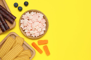Different baby finger foods on yellow background, flat lay. Space for text