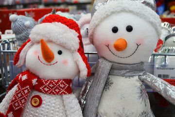 Two toy snowmen stand on a shelf in a store. sale of New Year and Christmas tree decorations.