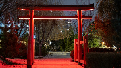 Fototapeta na wymiar Red Japanese-style gates in the park, highlighted in red. The concept of landscape design.