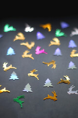 Reindeer and Christmas tree confetti on dark background. Selective focus.