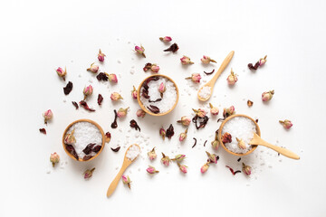 Wooden bowls filled with white bath sea salt with dry rose buds. Beauty treatment for spa and...