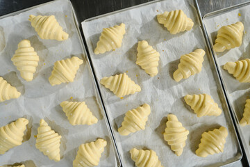 Beautiful raw croissants before baking on a baking sheet. Bakery production. Classic French pastries. Close up High quality photo