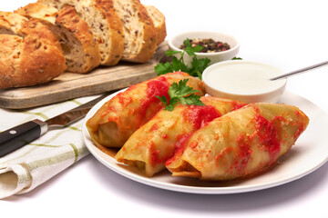 Portion of cabbage rolls stuffed with ground beef and rice with sour cream on a plate