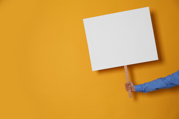 Woman holding blank sign on yellow background, closeup. Space for text