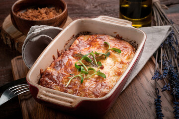 Lasagna with meat and tomato sauce baked in the oven in a ceramic dish. Homemade lasagna bolognese on a wooden table