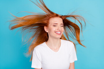 Photo of young cheerful girl happy positive smile air fly wind volume haircare isolated over blue...