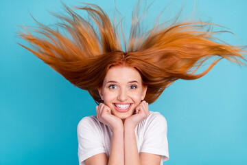 Photo of young cheerful girl happy positive smile hands touch chin fly air hair isolated over blue color background