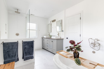 An elegant, renovated white bathroom with a standalone tub, stand up shower with subway tiles and...