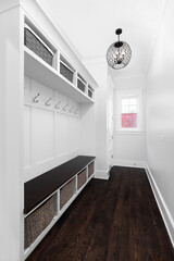 A luxurious mud room with built-in bench seating, coat hooks, and bins in small cubes for storage....