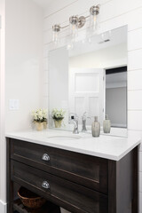 Fototapeta na wymiar A beautiful bathroom with a shiplap wall, dark wood vanity cabinet, and a marble countertop. 