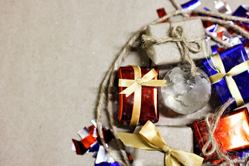 Merry Christmas, Happy New Year and Boxing day concept. Present boxes, world gloge crystal glass, pine tree and house models on light brown background.