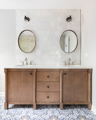 A cozy bathroom with a patterned tile floor, natural wood vanity, tiled backsplash, and lights...
