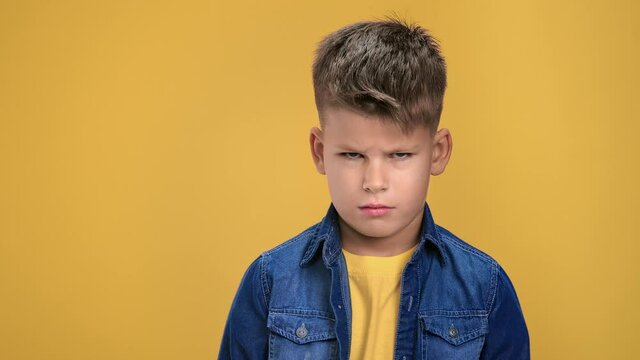 Closeup portrait of sad kid boy frowning thinking about problem solving posing isolated on orange