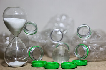 Plastic pollution. Empty plastic bottle, plastic bag and wolrd globe crystal glass with sand running through hourglass on table. Countdown timer for global warimg concept.