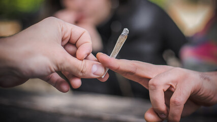 Closeup view of marijuana joint circling around hand to hand