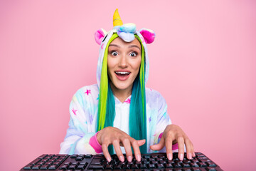 Portrait of attractive amazed cheery girl wearing kigurumi typing chatting isolated over pink pastel color background © deagreez