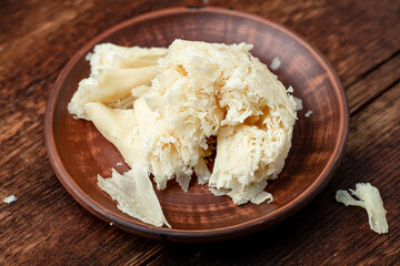 Hard cheese sliced chips on a clay plate on a wooden background.