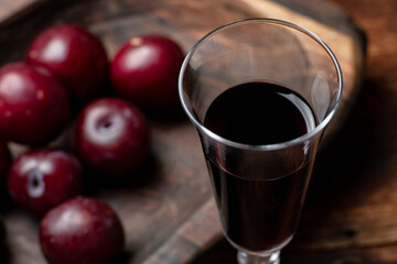Plum red wine on a dark wooden background. Glass with red wine close up.