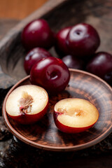 Fresh sliced red plums on a dark wooden background.