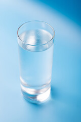 Glass of pure cold water on a blue background.