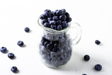 Blueberries in a glass jug on a white background. The benefits of berries, vegetarianism concept.