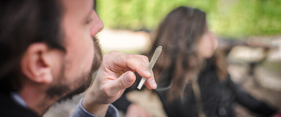 Young couple, woman and man, smoking cannabis marijuana ganja joint