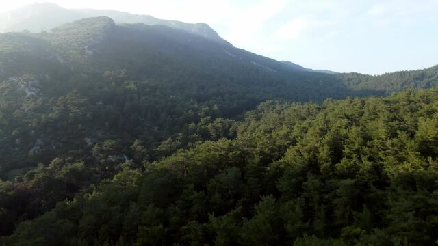 Aerial landscape footage of the hills and mountains with sun rays and some clouds.