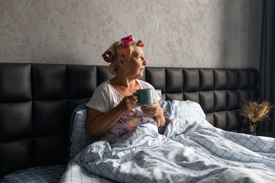 Beautiful 40-50 Years Old Relaxing Woman Enjoying Stress Free Weekend Sunny Morning Holding Cup In Bed In A Cozy Room